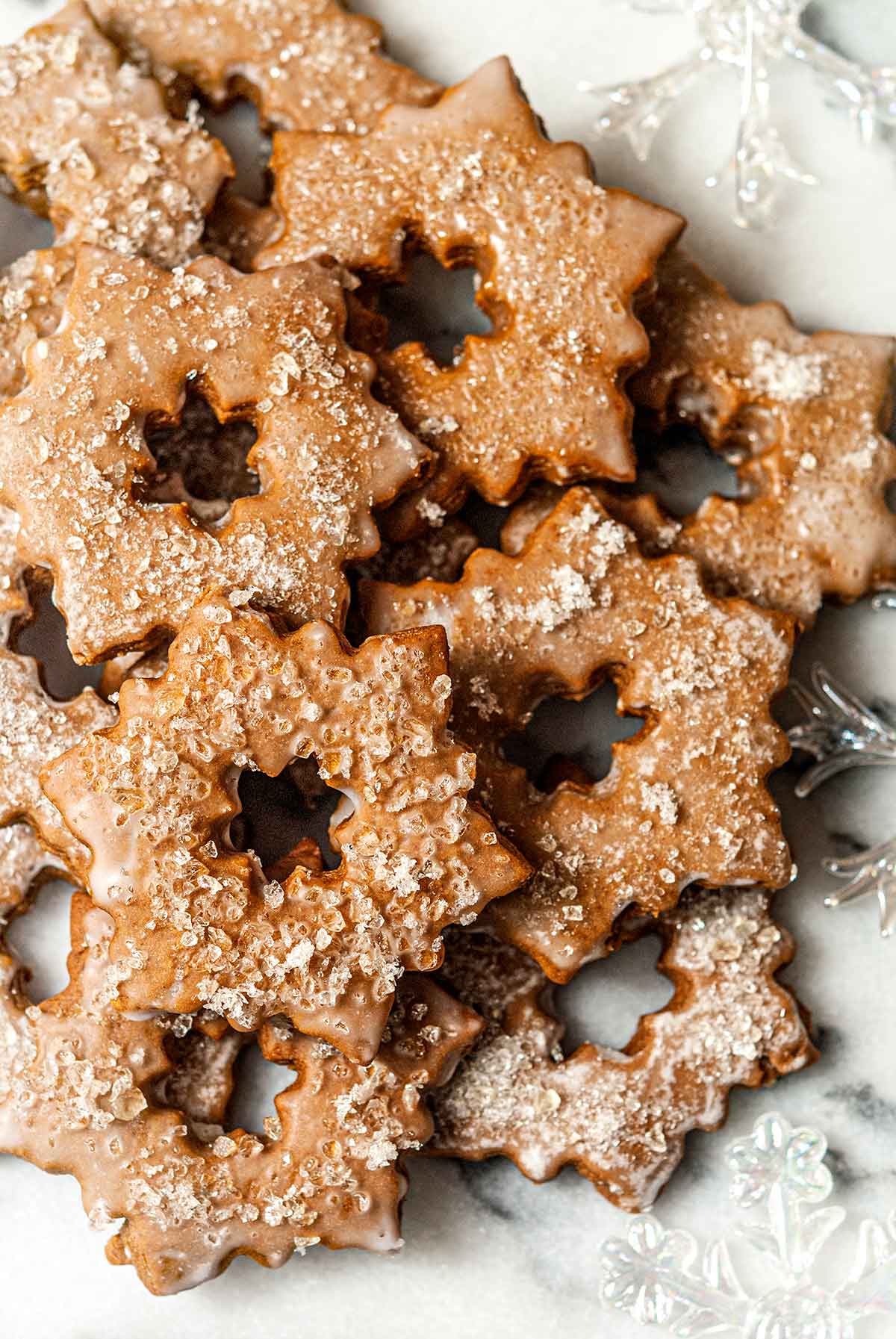 A pile of glazed, sugared gingerbread cookies on marble.