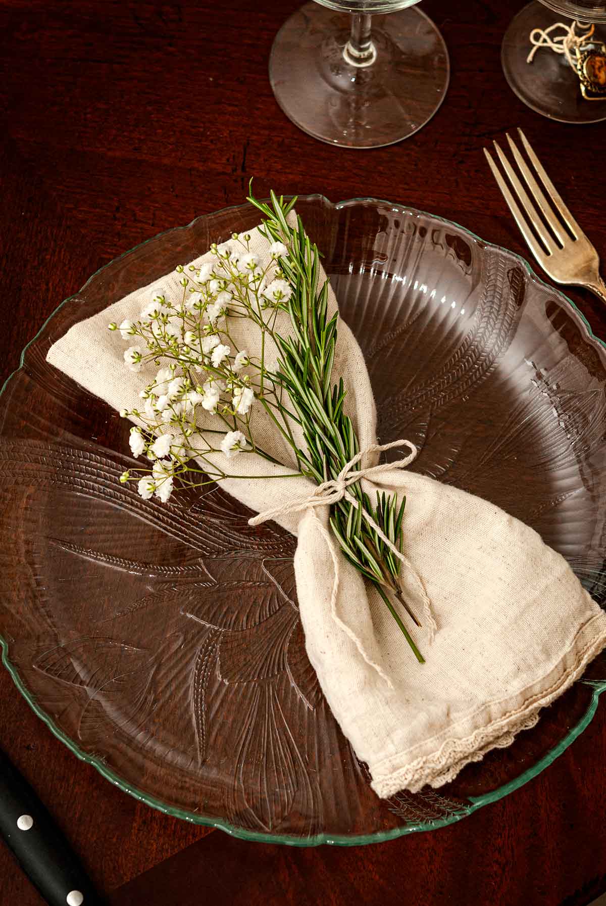 A plate with a napkin with baby's breath and rosemary.