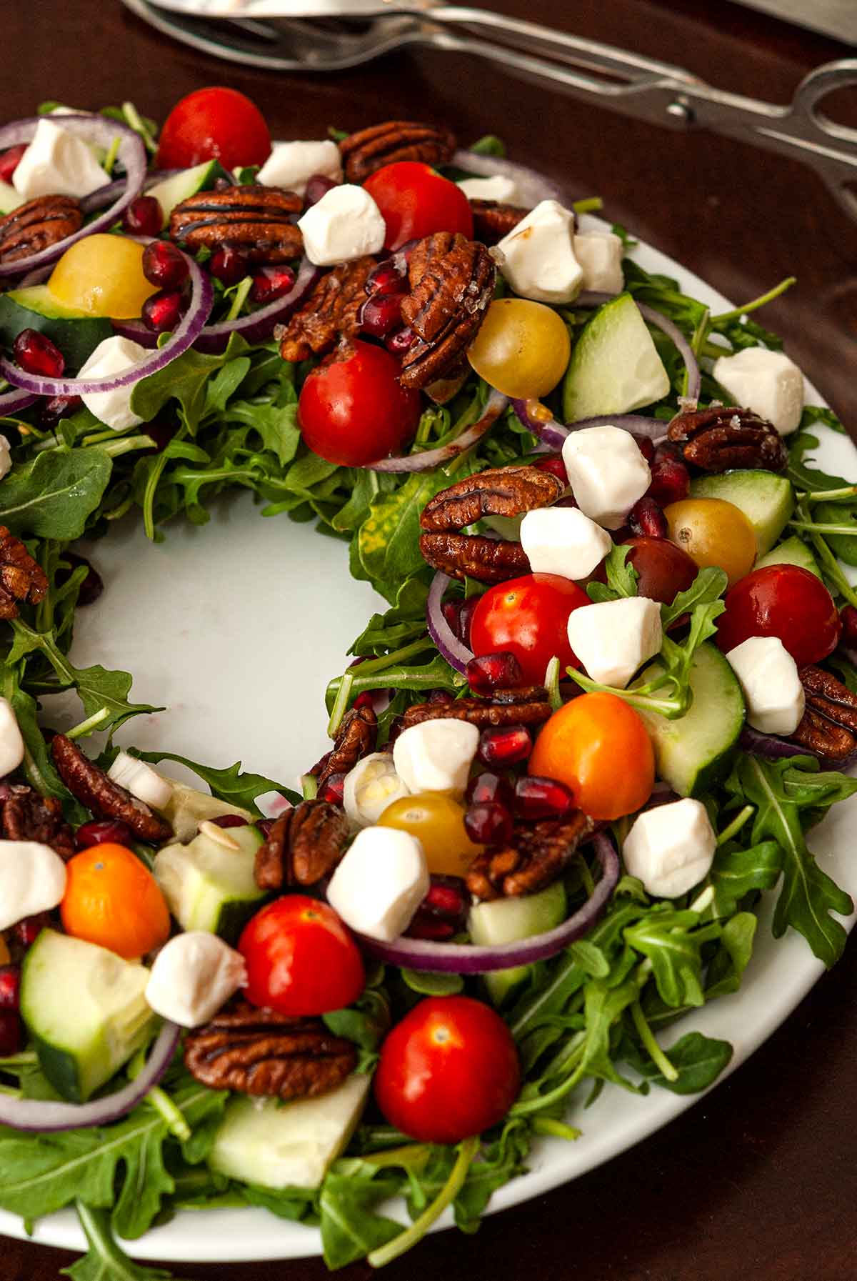 A salad that looks like a Christmas wreath on a table.