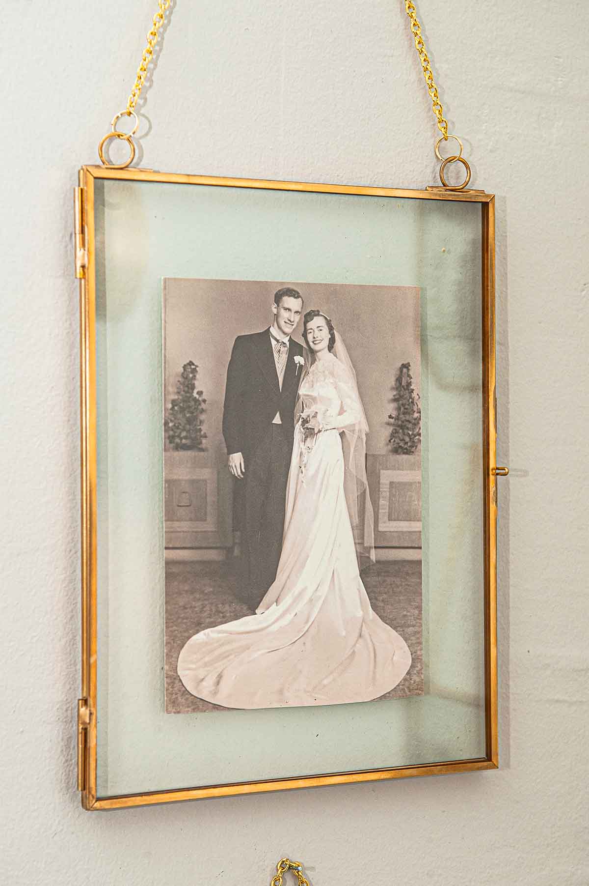 A vintage wedding photo in a clear frame on a wall.