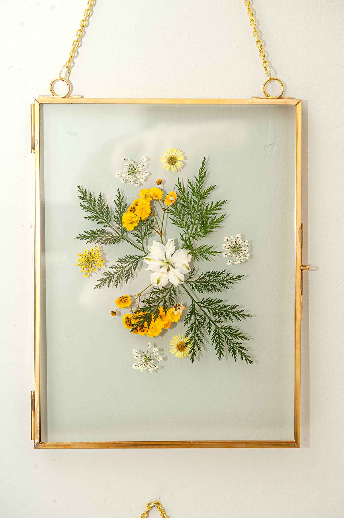 A frame with flowers and leaves on a wall.