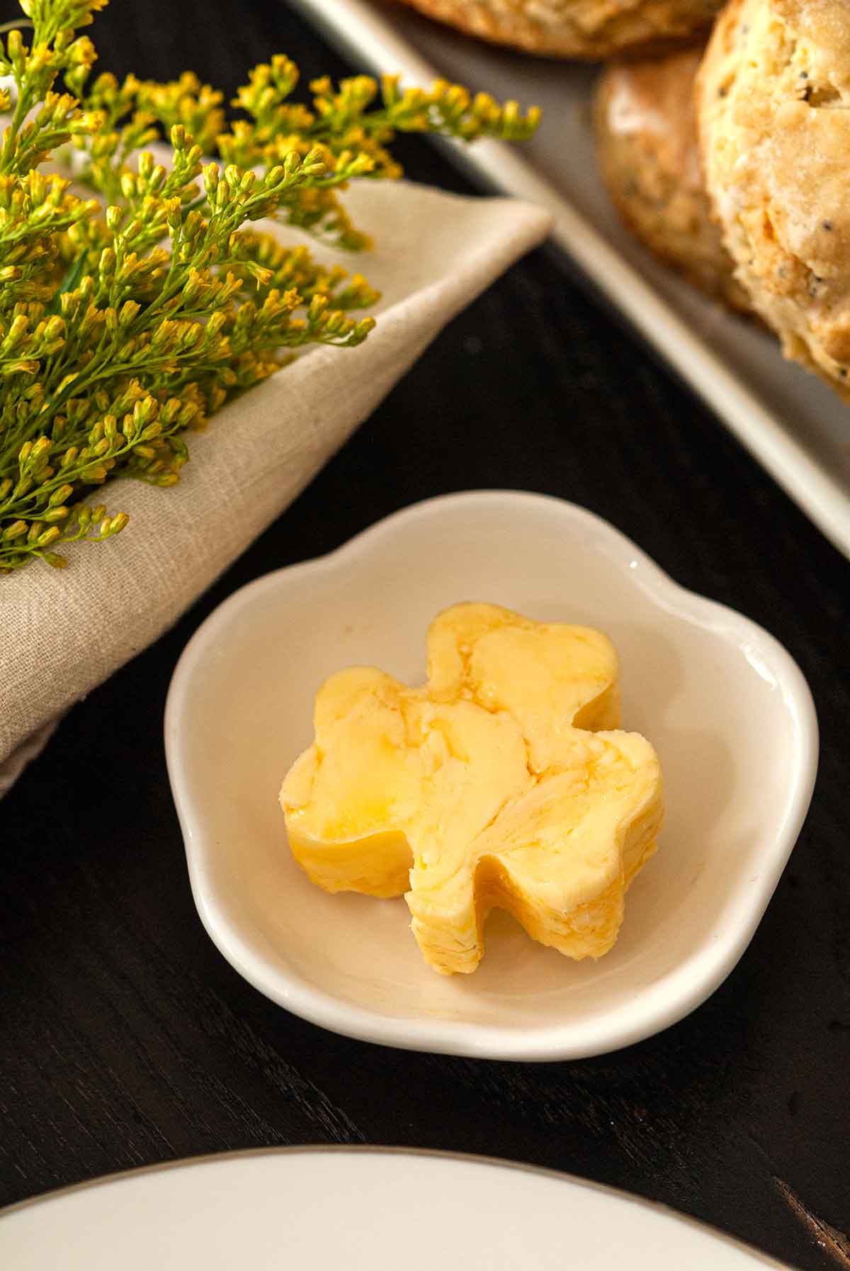 A small bowl with a pad of shamrock-shaped honey butter.