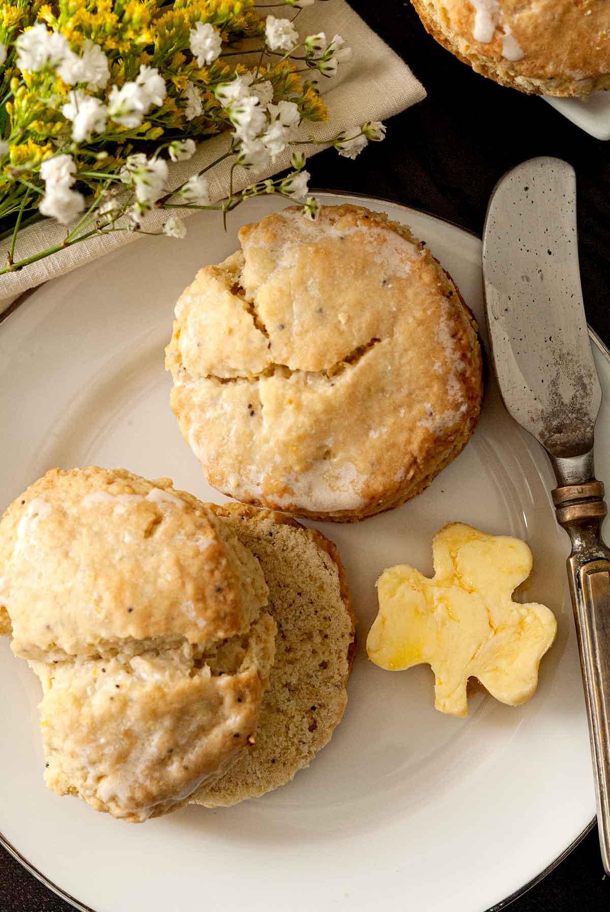 2 scones on a plate beside shamrock-shaped butter and a knife.
