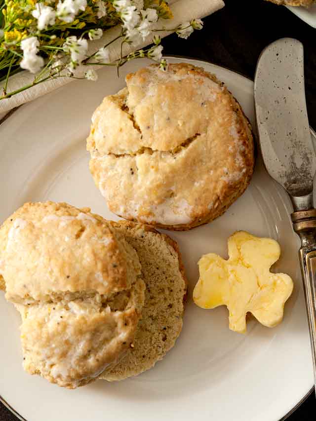 2 scones on a plate beside shamrock-shaped butter and a knife.