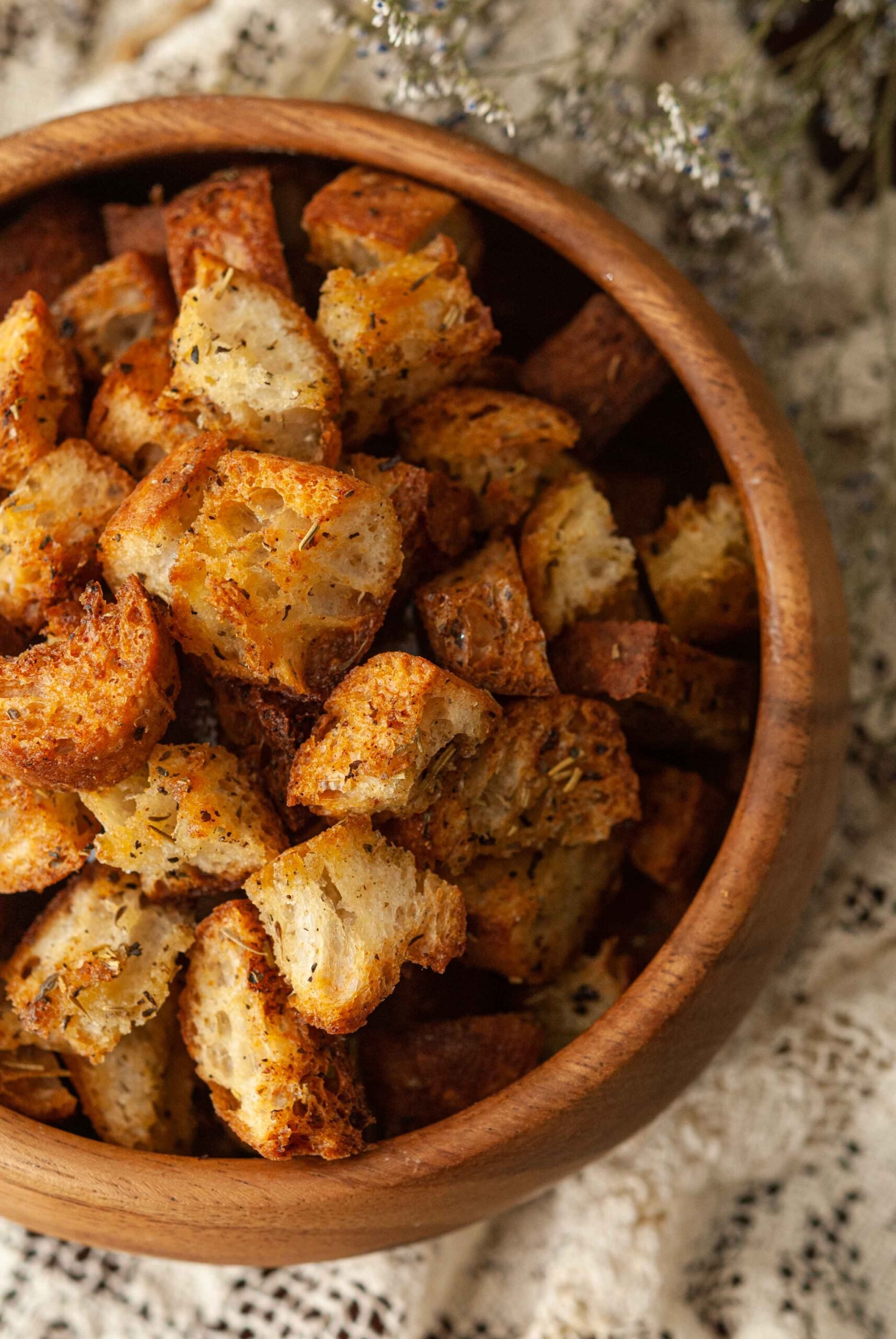Croutons in a wooden bowl on a lace table cloth.