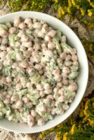 Chickpea salad with dill on a lace tablecloth surrounded by flowers.