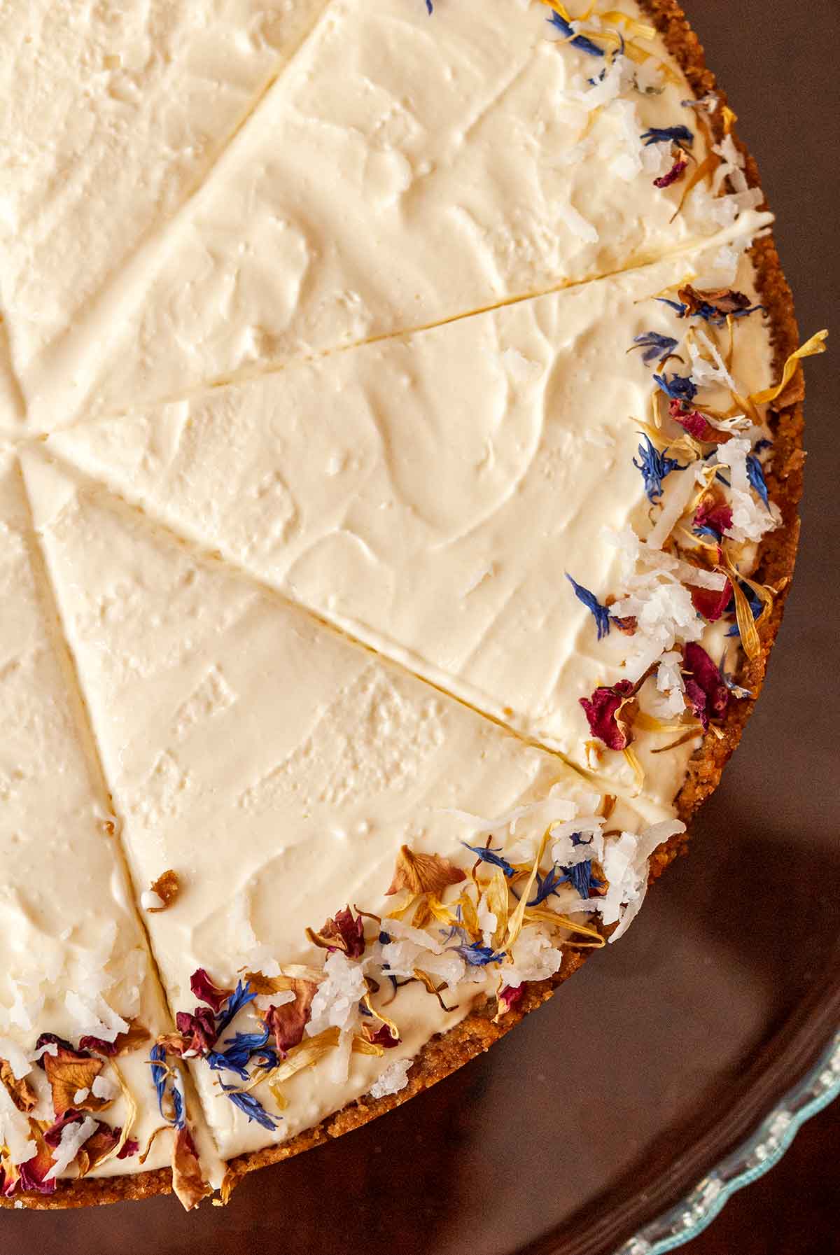 A sliced coconut cheesecake, garnished with coconut and flowers.