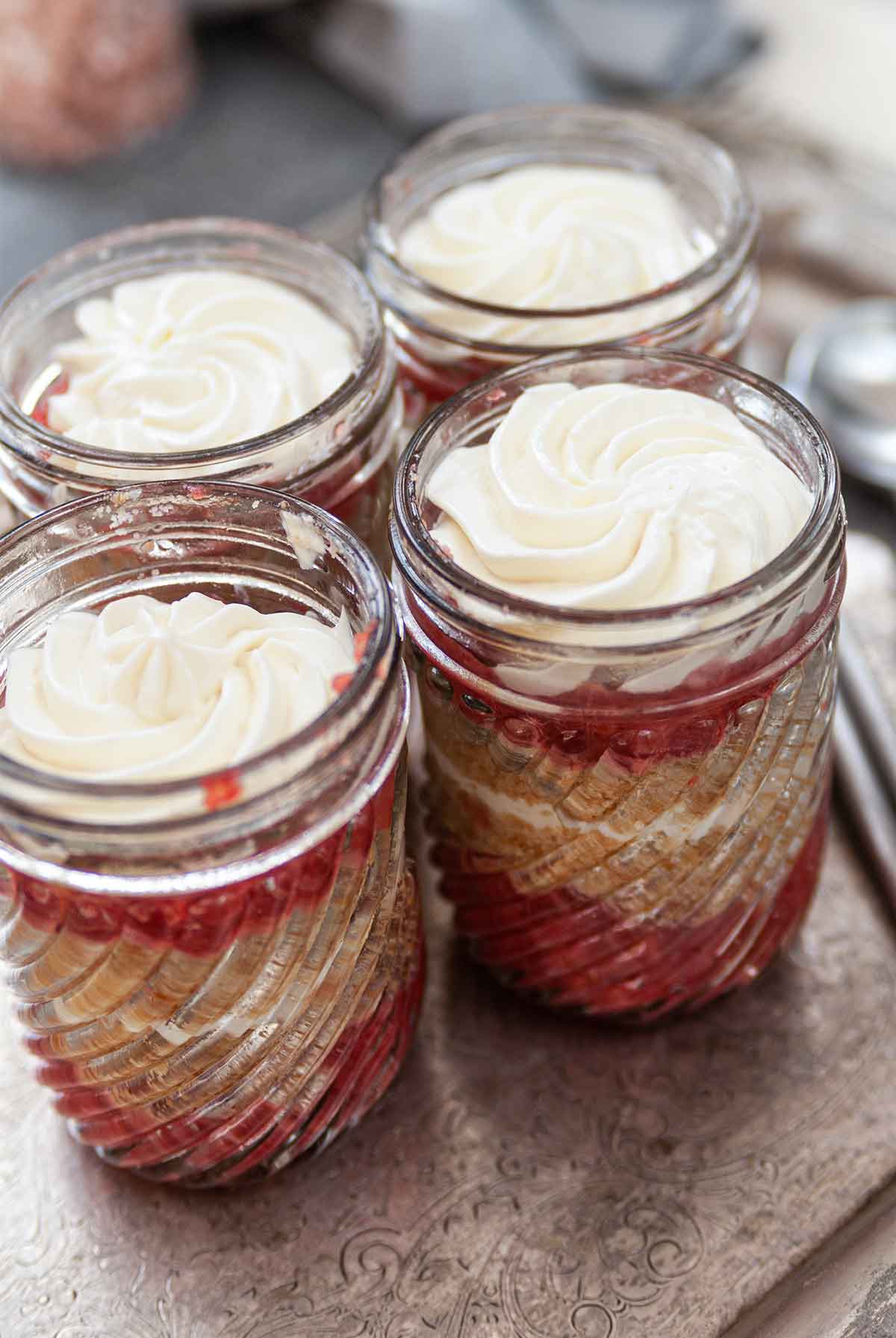 4 cups of strawberry-rhubarb and cheesecake mousse on a metal platter.