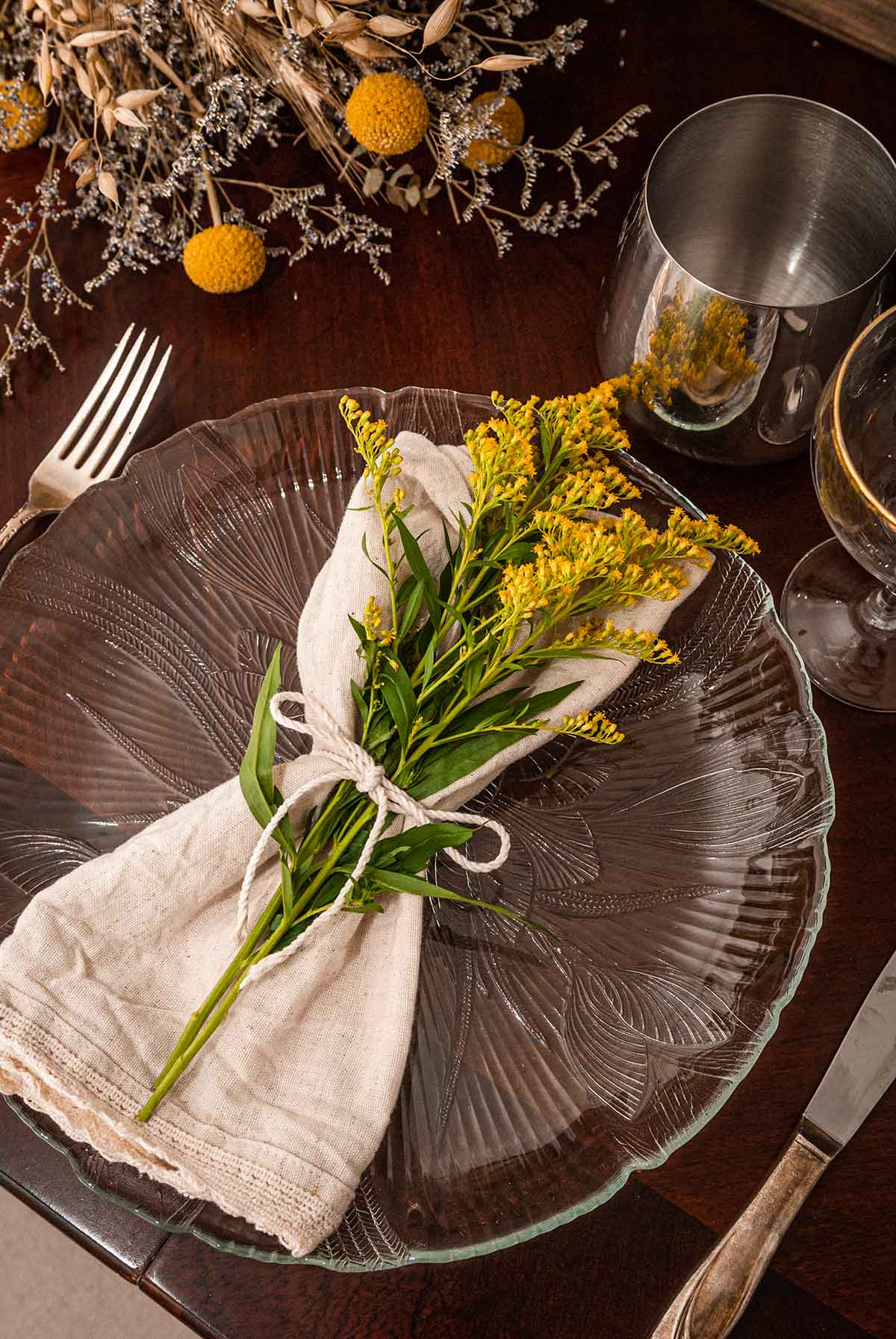 A plate with a napkin with flowers beside other flowers.