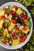 A bowl of brightly colored corn salad with little flowers.