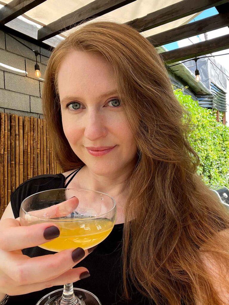 Genevieve Morrison holding a cocktail in a back yard.