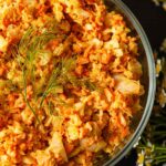 Curried coleslaw in a bowl topped with fennel fronds.