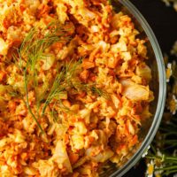 Curried coleslaw in a bowl topped with fennel fronds.