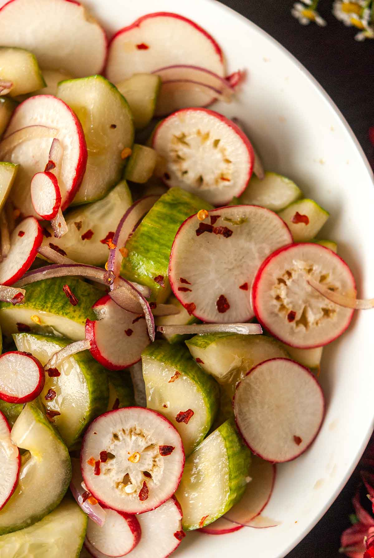 A bowl of ponzu cucumbers and radishes in a bowl.