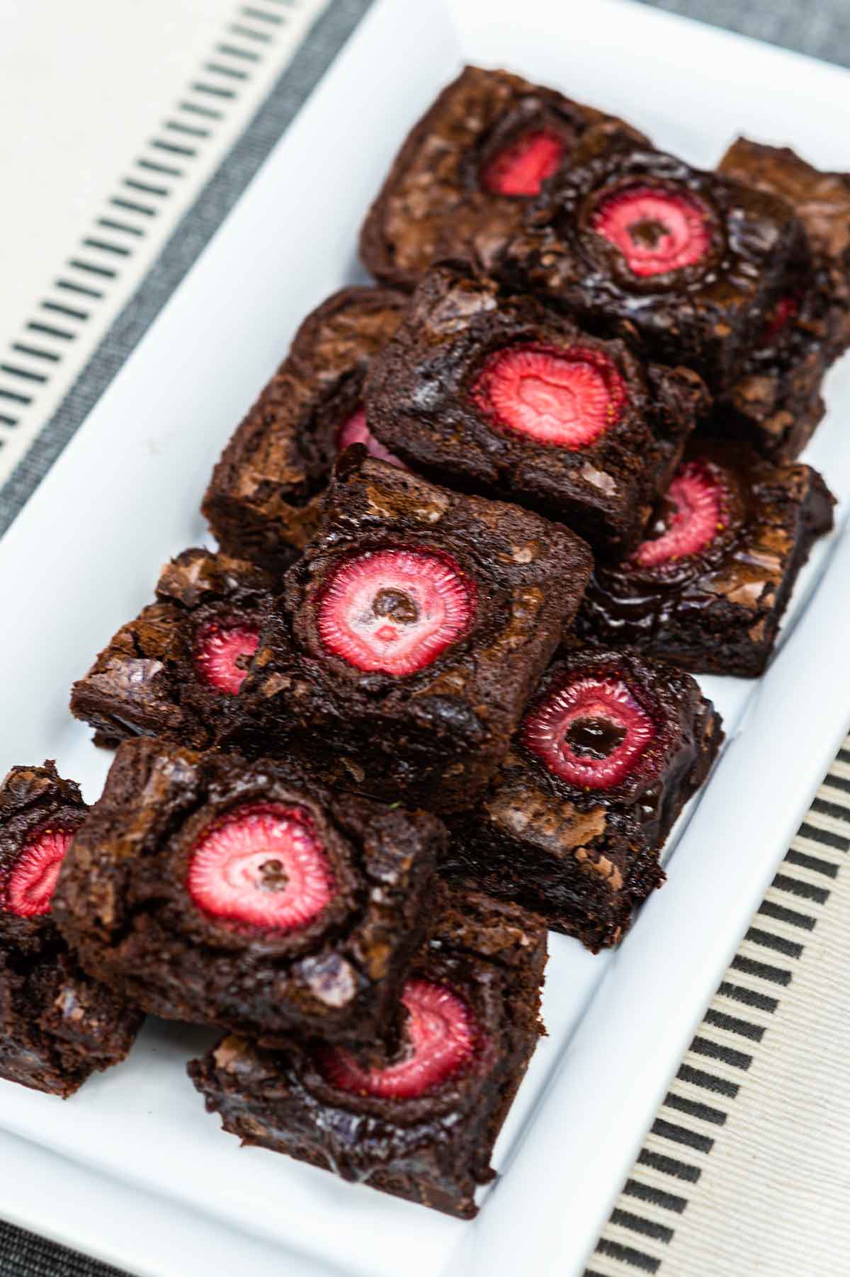 A plate of brownies topped with strawberries.