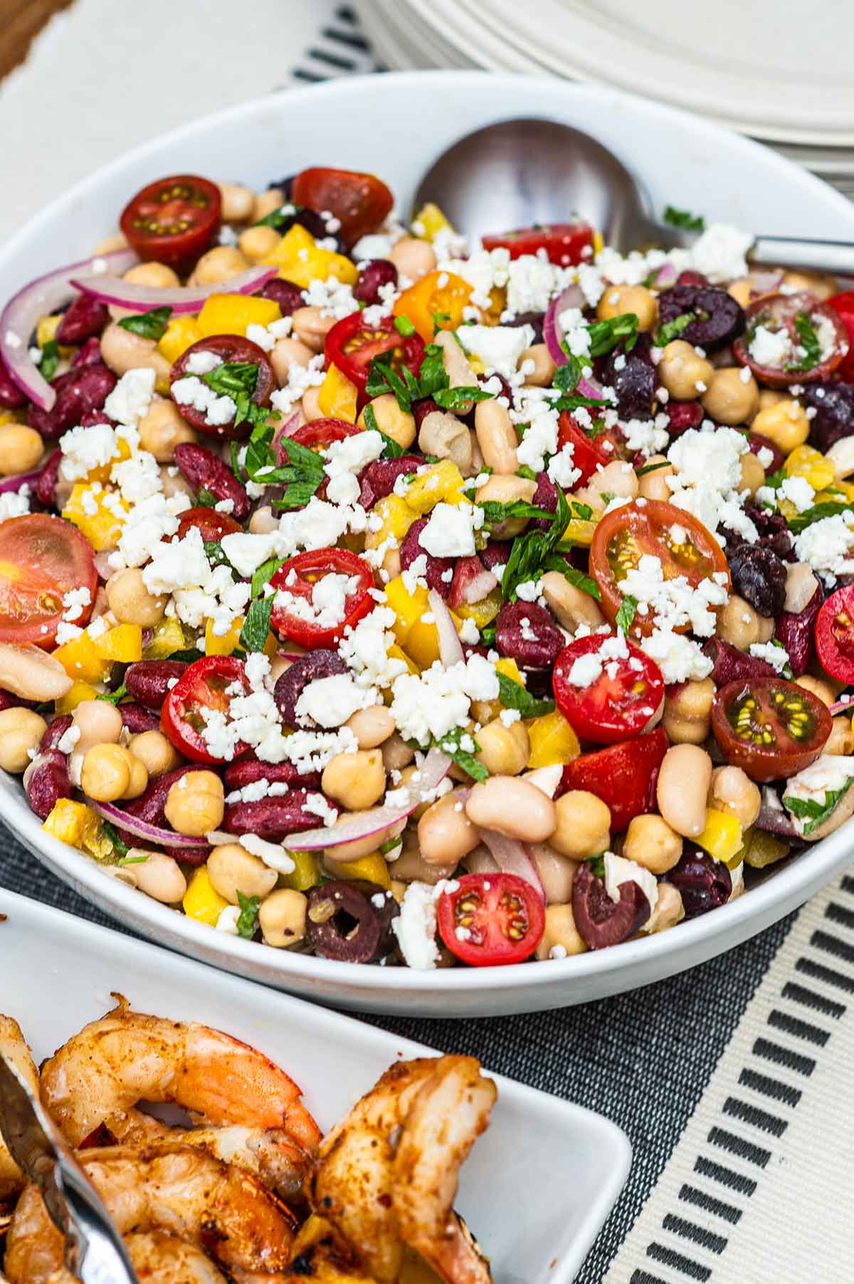 A bowl of 3 bean salad on a table, sprinkled with feta.