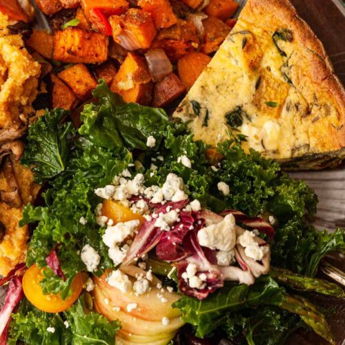A plate of salad, quiche, and potatoes.