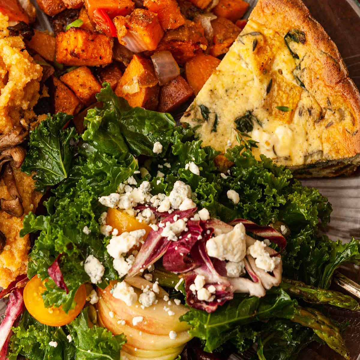 A plate of salad, quiche, and potatoes.