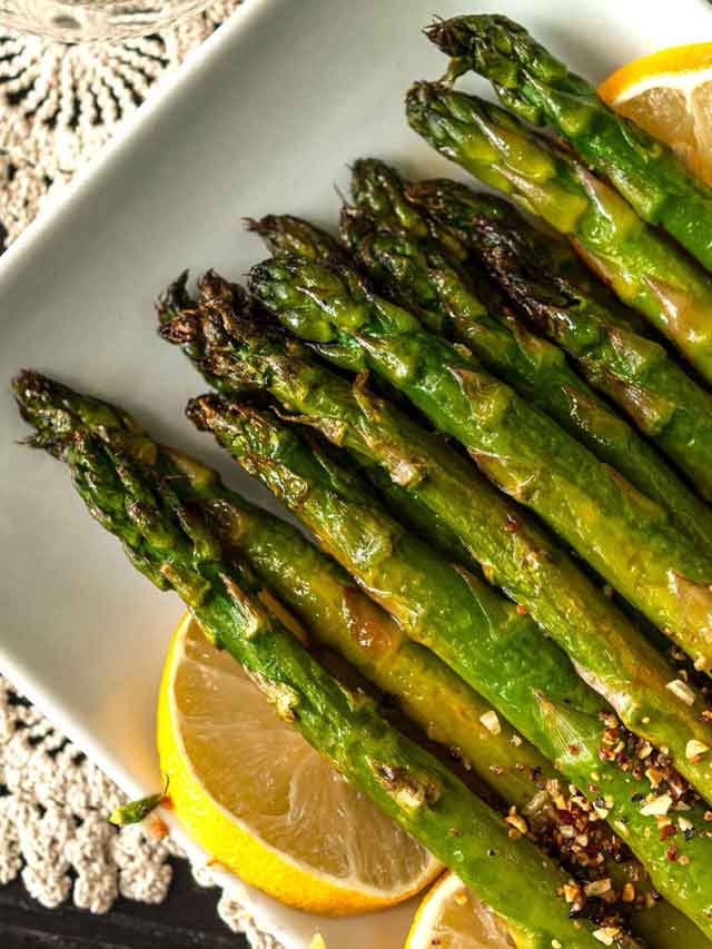 Crispy asparagus tips on a plate, garnished with lemons.