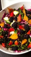 A colorful beet salad in a bowl with blackberries.