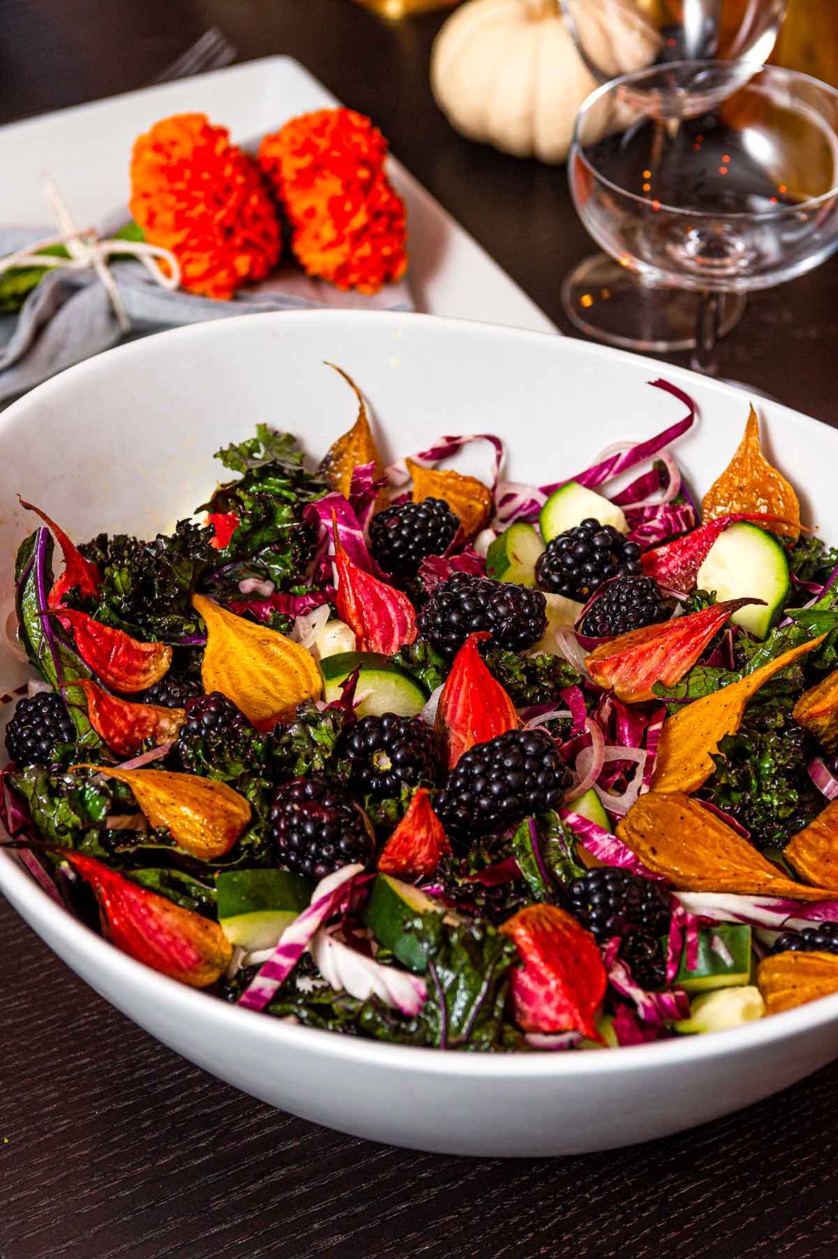 A colorful beet salad in a bowl beside marigolds in a napkin.