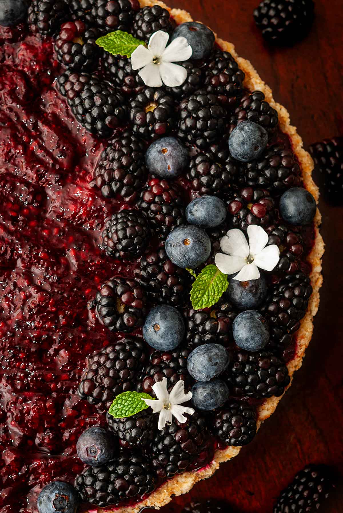 The top of a cheesecake garnished with flowers and berries.