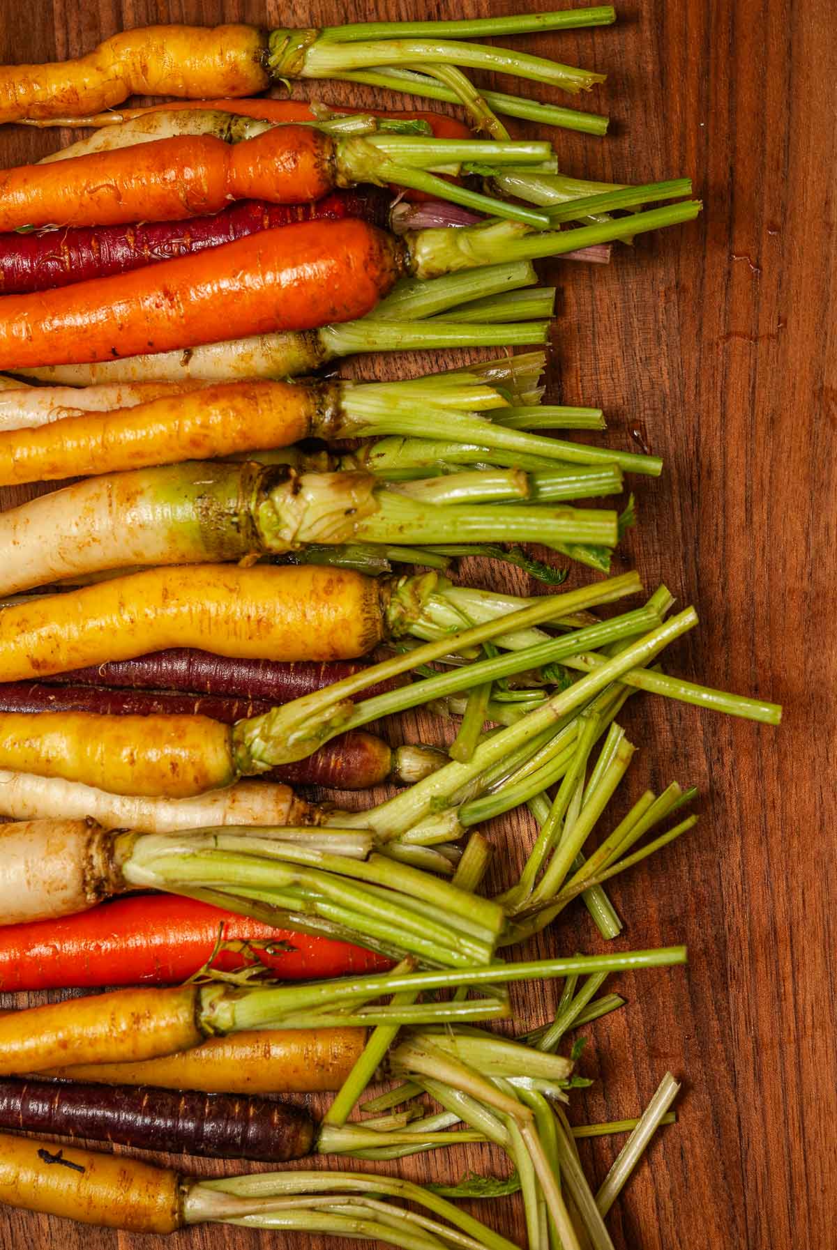 Rainbow carrots on a cutting board with sliced stems.