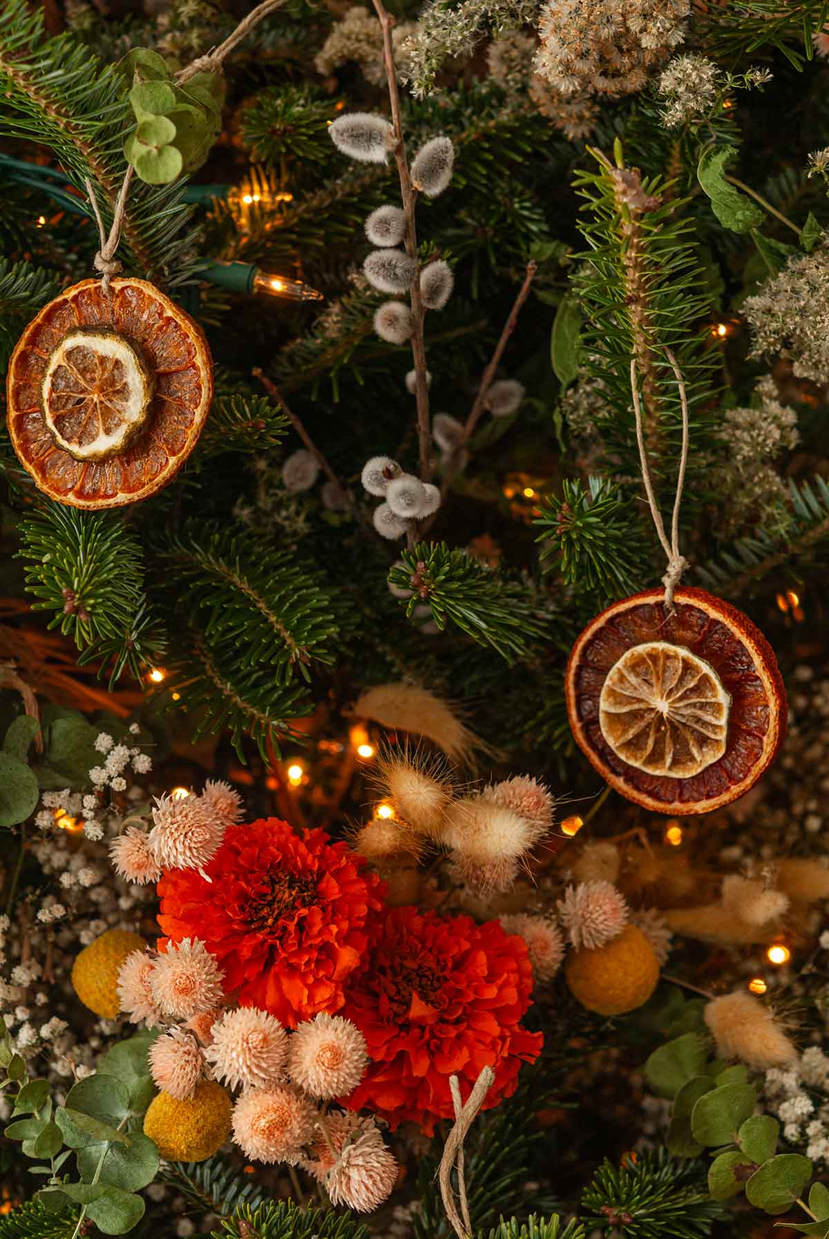 2 citrus ornaments hanging on a christmas tree covered in flowers.