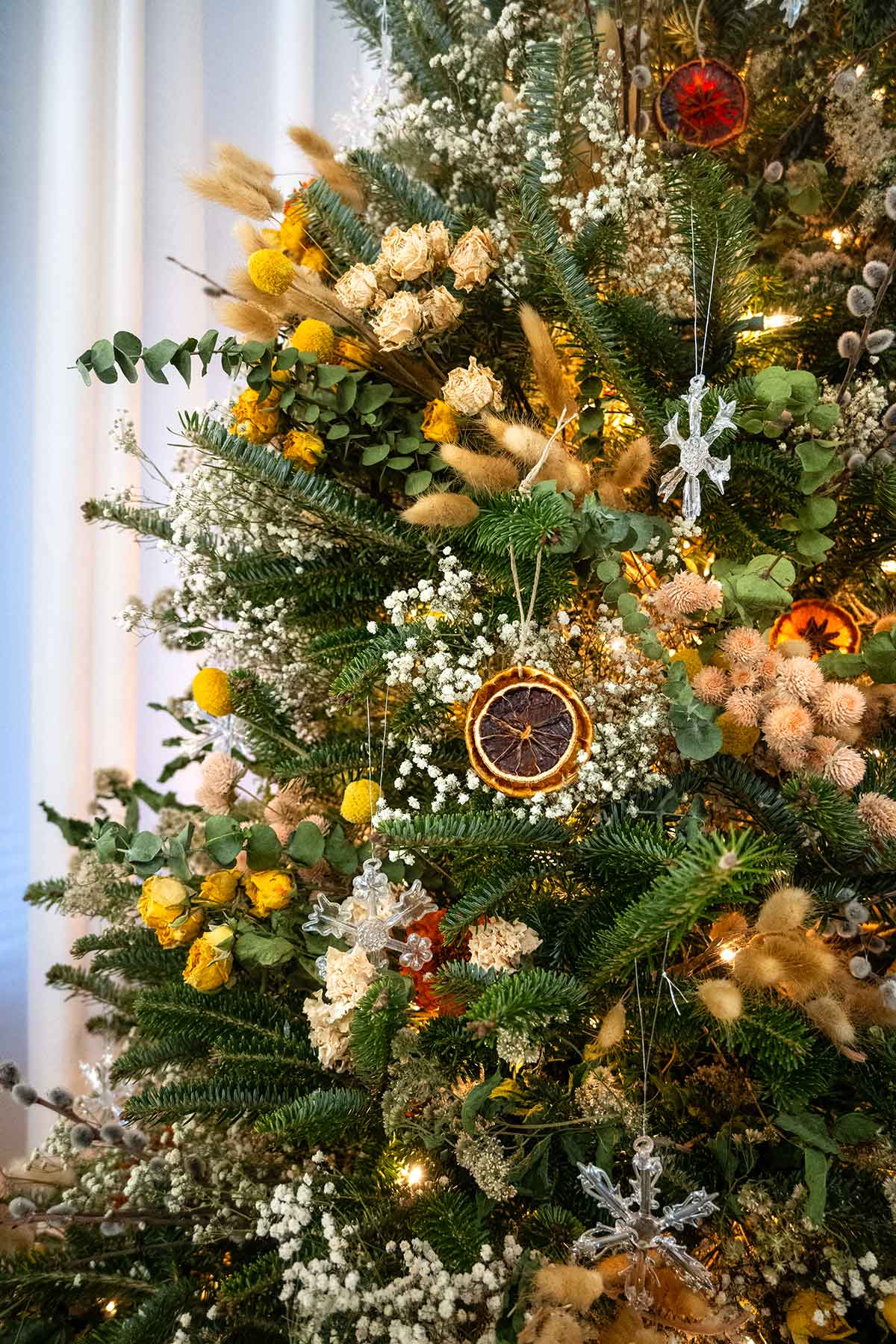 A christmas tree decorated with flowers and citrus ornaments.