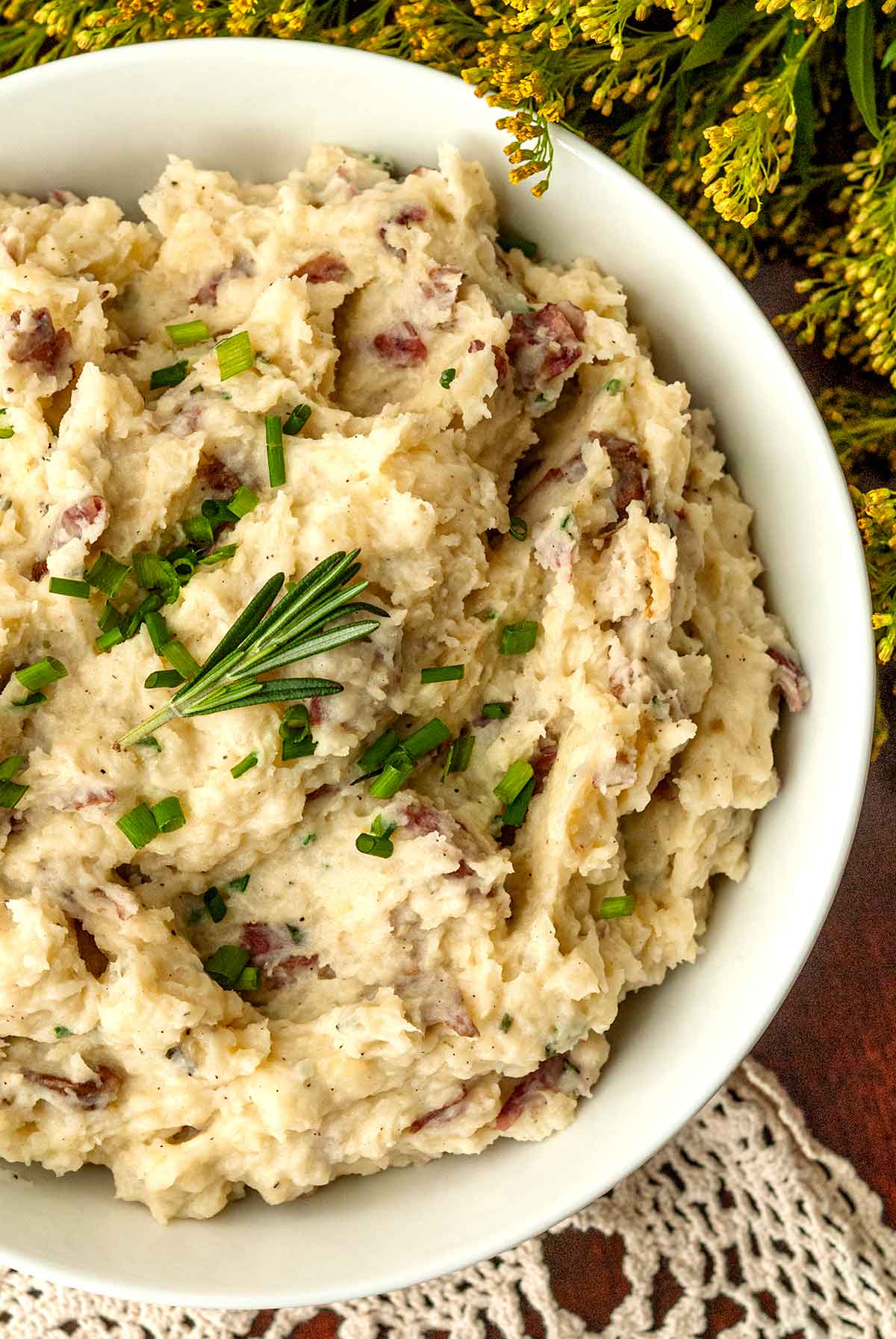 Rosemary on the top of herbed mashed potatoes in a bowl.