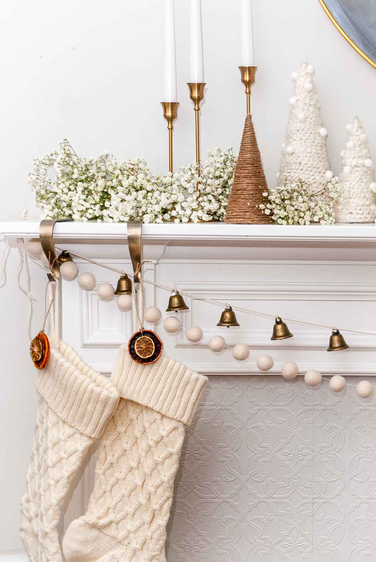 2 christmas stockings hanging from a minimally designed mantle with baby's breath.