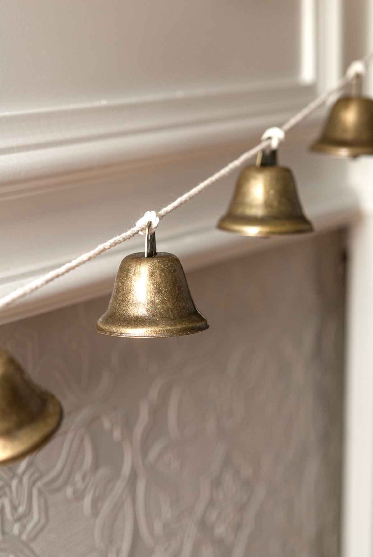 4 hanging bells on a mantle.