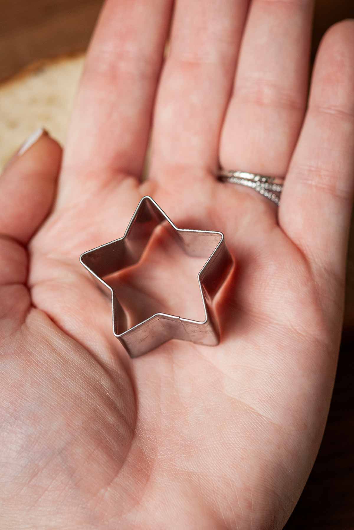 A hand holding a star-shaped cookie cutter.