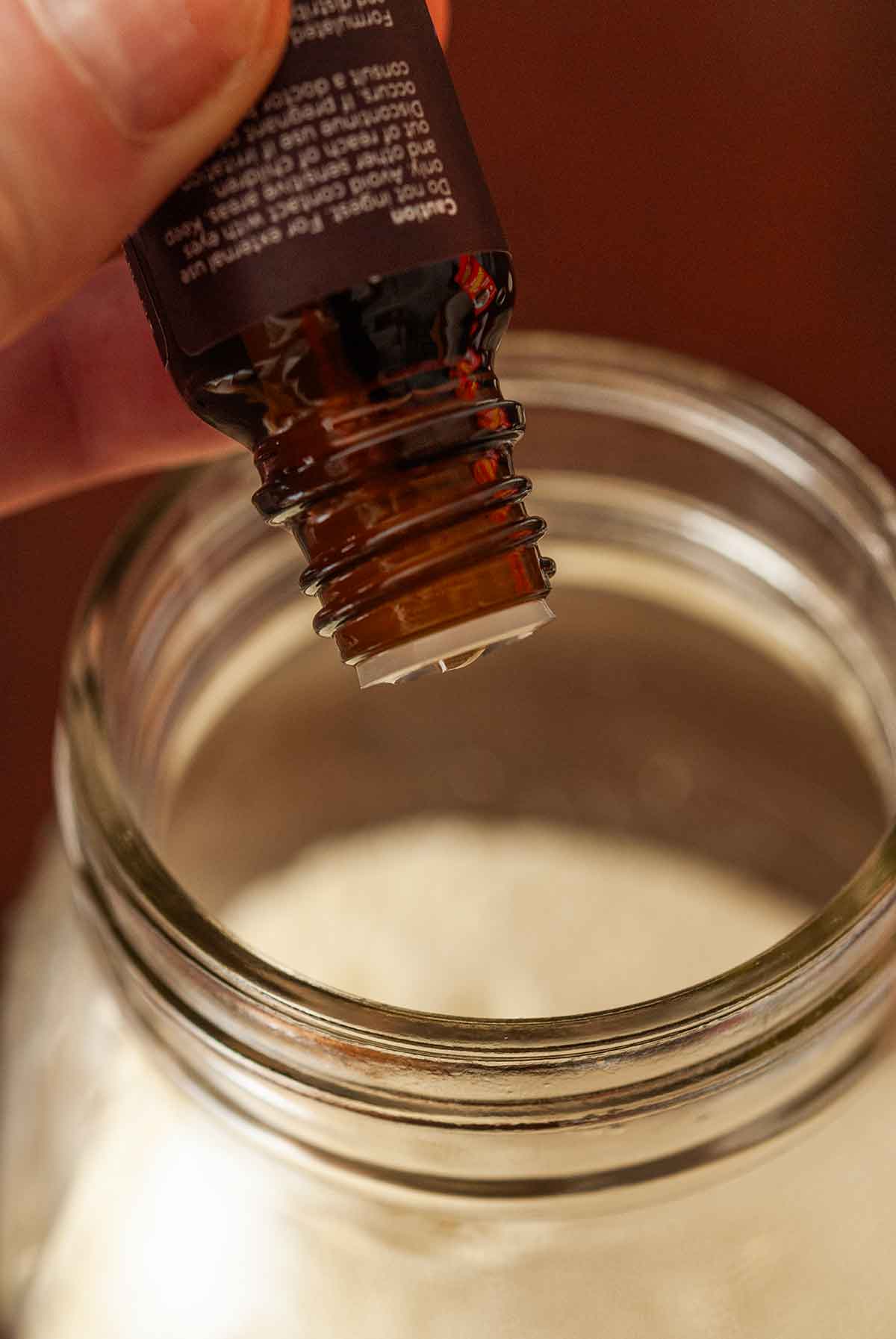 A small jar of oil dripping into milk in a jar.