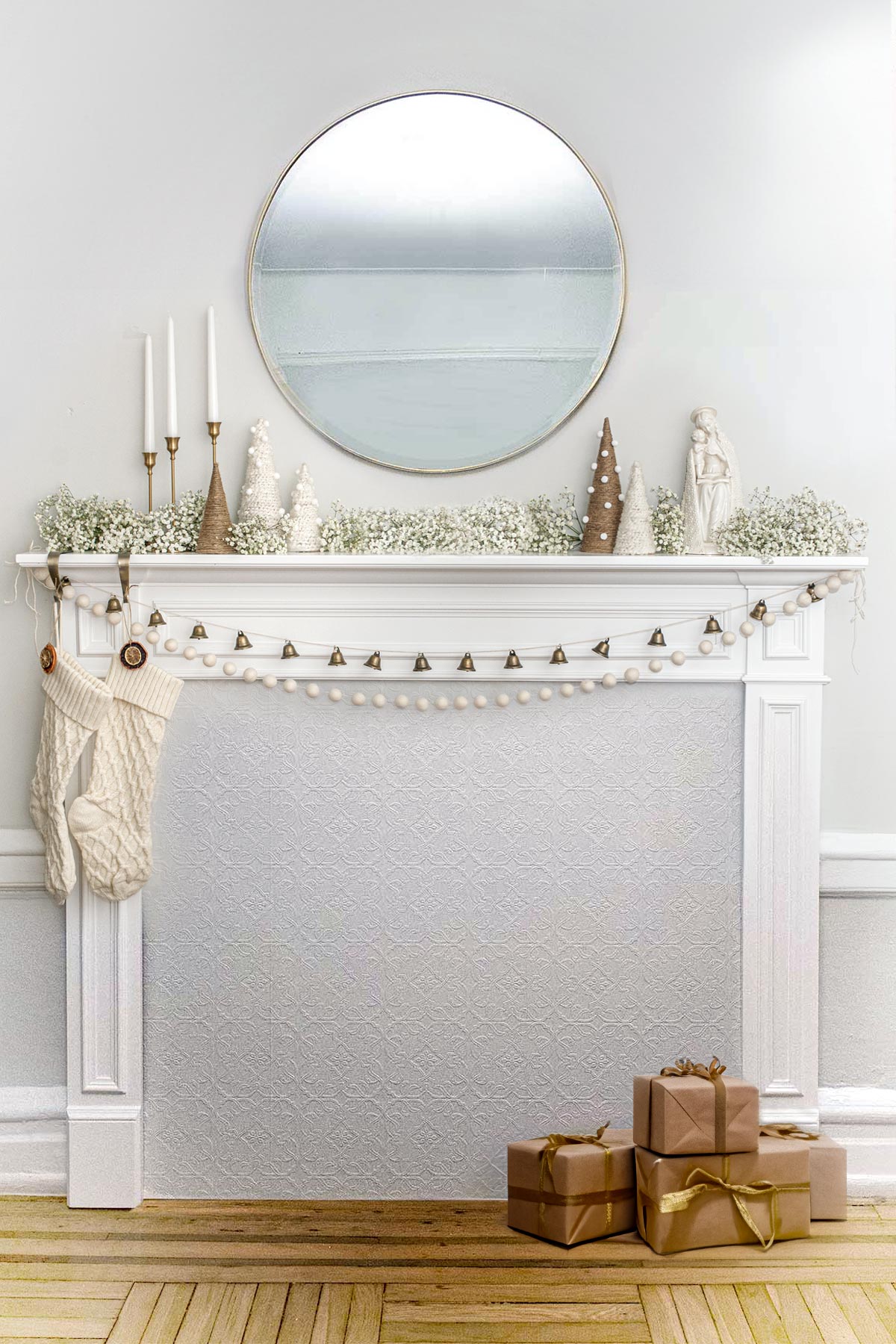 A minimally designed Christmas mantle with baby's breath and presents on the ground.