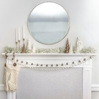 A minimally designed Christmas mantle with baby's breath and presents on the ground.