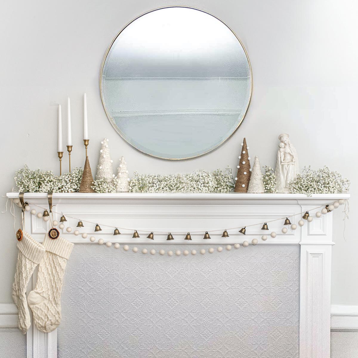 A minimally designed Christmas mantle with baby's breath and presents on the ground.