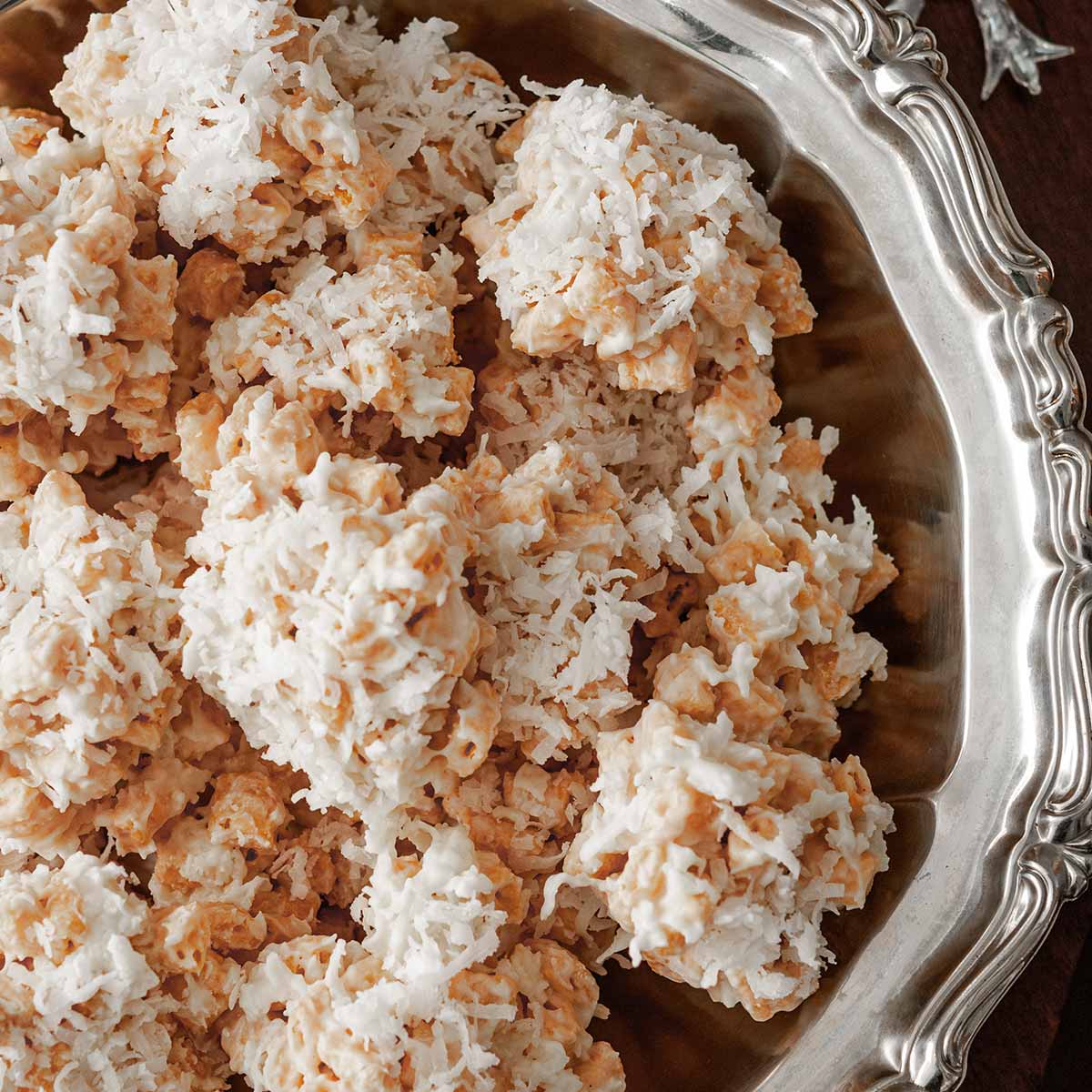 A decorative silver bowl full of coconut cookies.