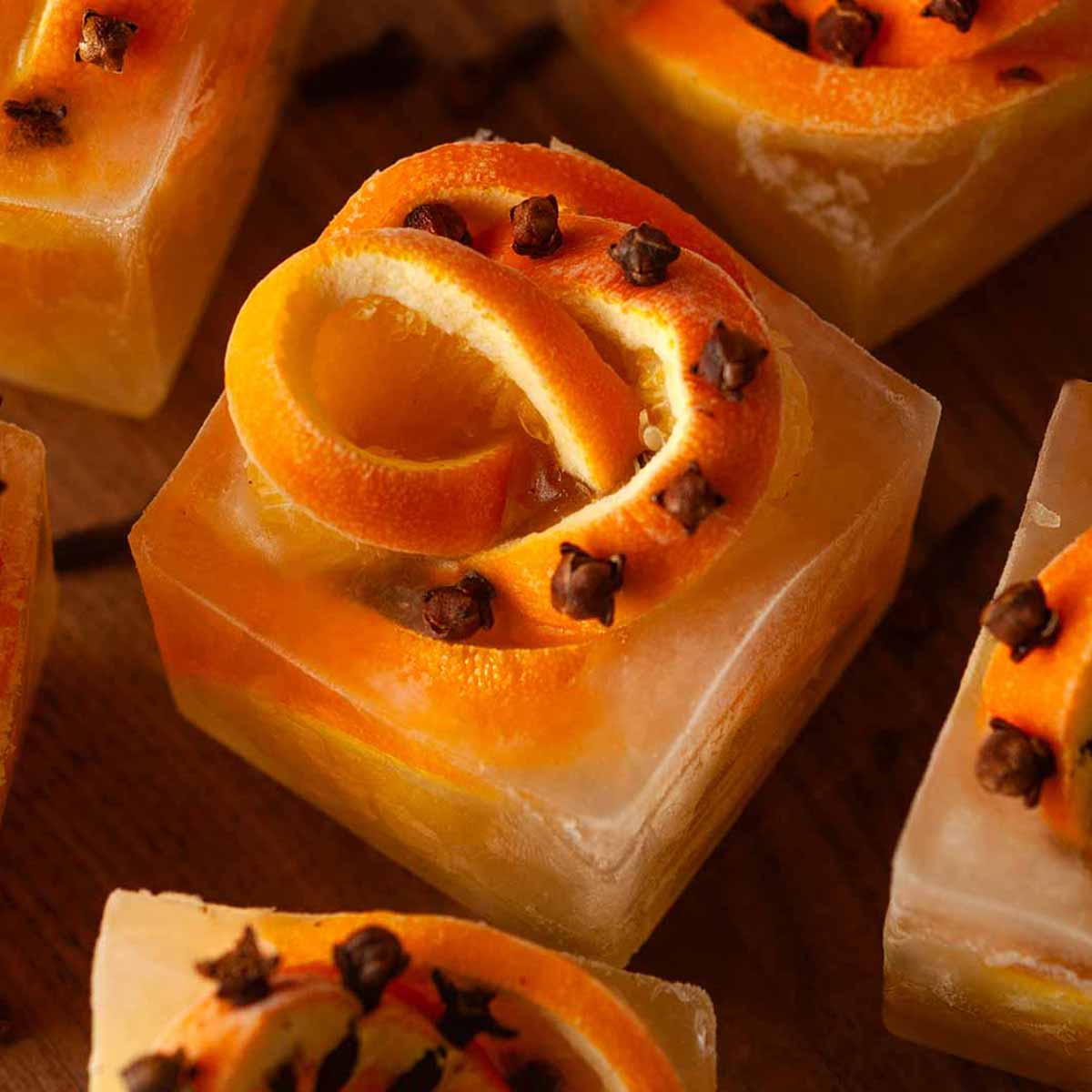 A clove orange ice cubes surrounded by cloves.