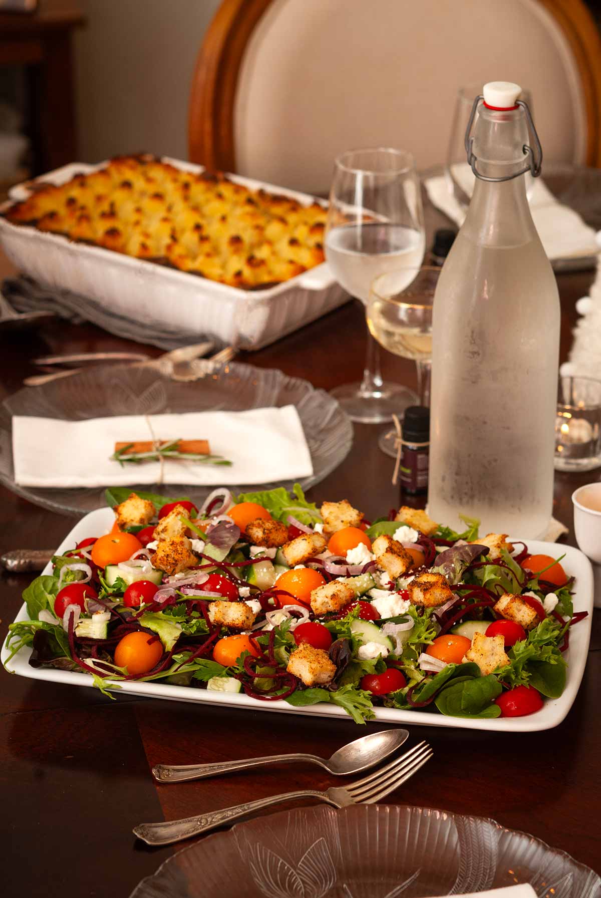 A festive salad with star-shaped croutons on a set dining table with shepherd's pie.