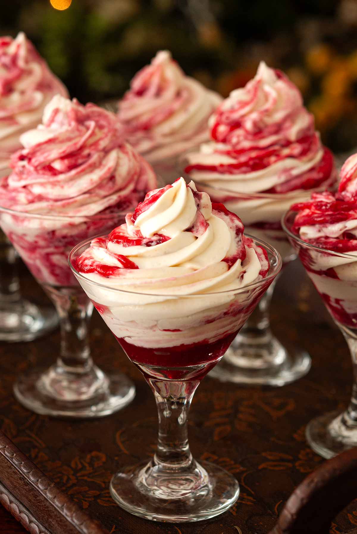 6 cheesecake mousse desserts on a tray in front of a christmas tree.