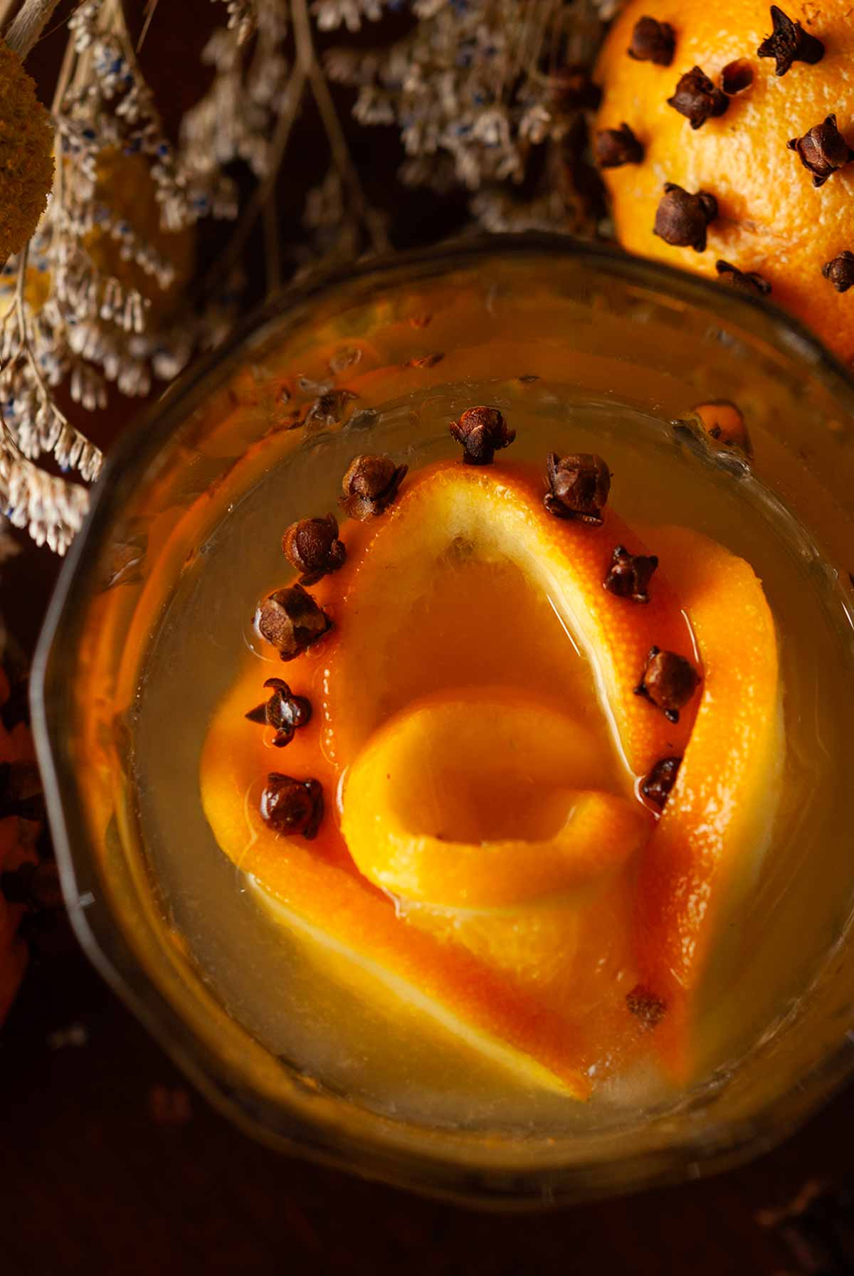 The top of a cocktail in front of a clove orange with a clove orange rose ice cube.