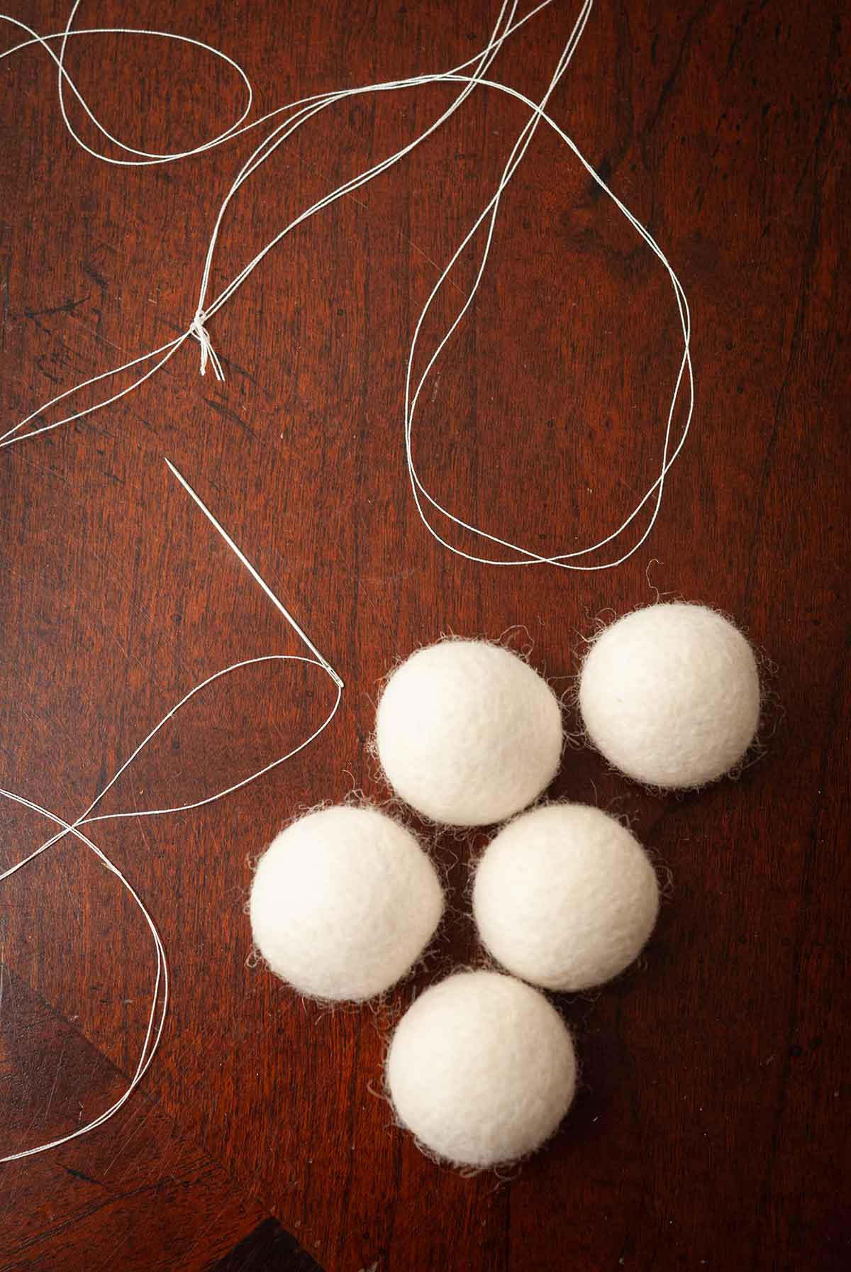 5 wool balls on a table with a needle and thread