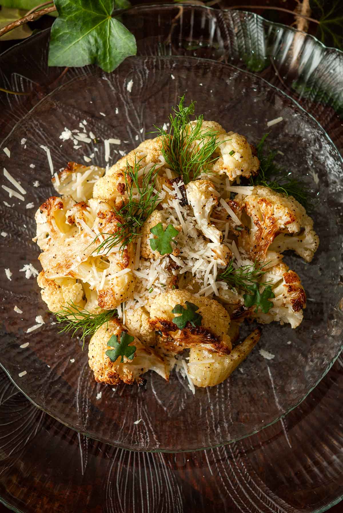 A plate of fennel and cauliflower, garnished with basil clovers, surrounded by ivy.