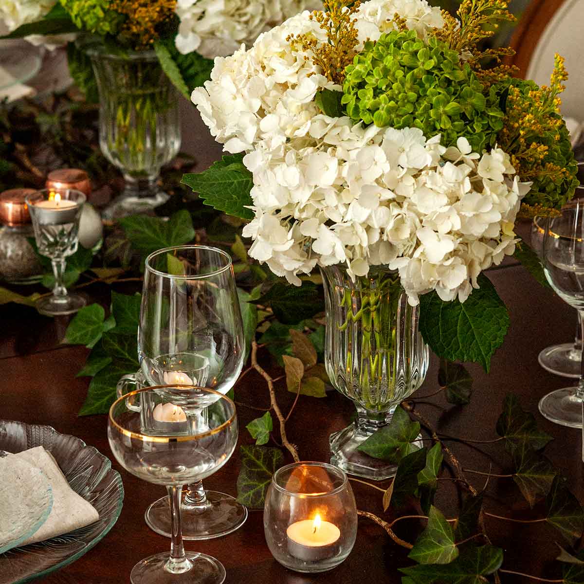 A table decorated with ivy, flowers, and small candles.