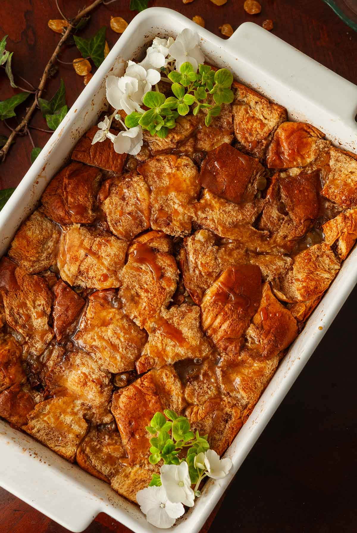 A pan of salted whisky caramel bread pudding garnished with flowers.