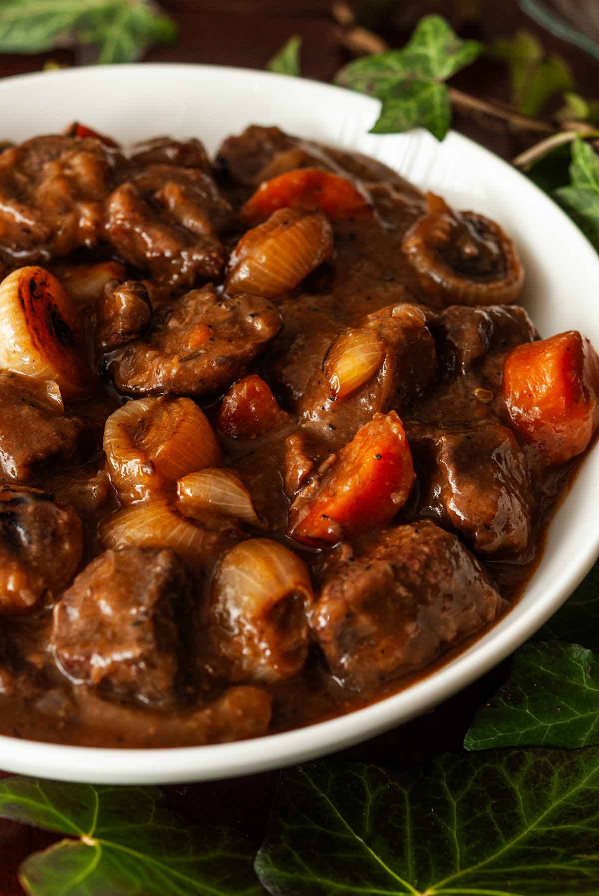 The side of a bowl of lamb stew surrounded by ivy.