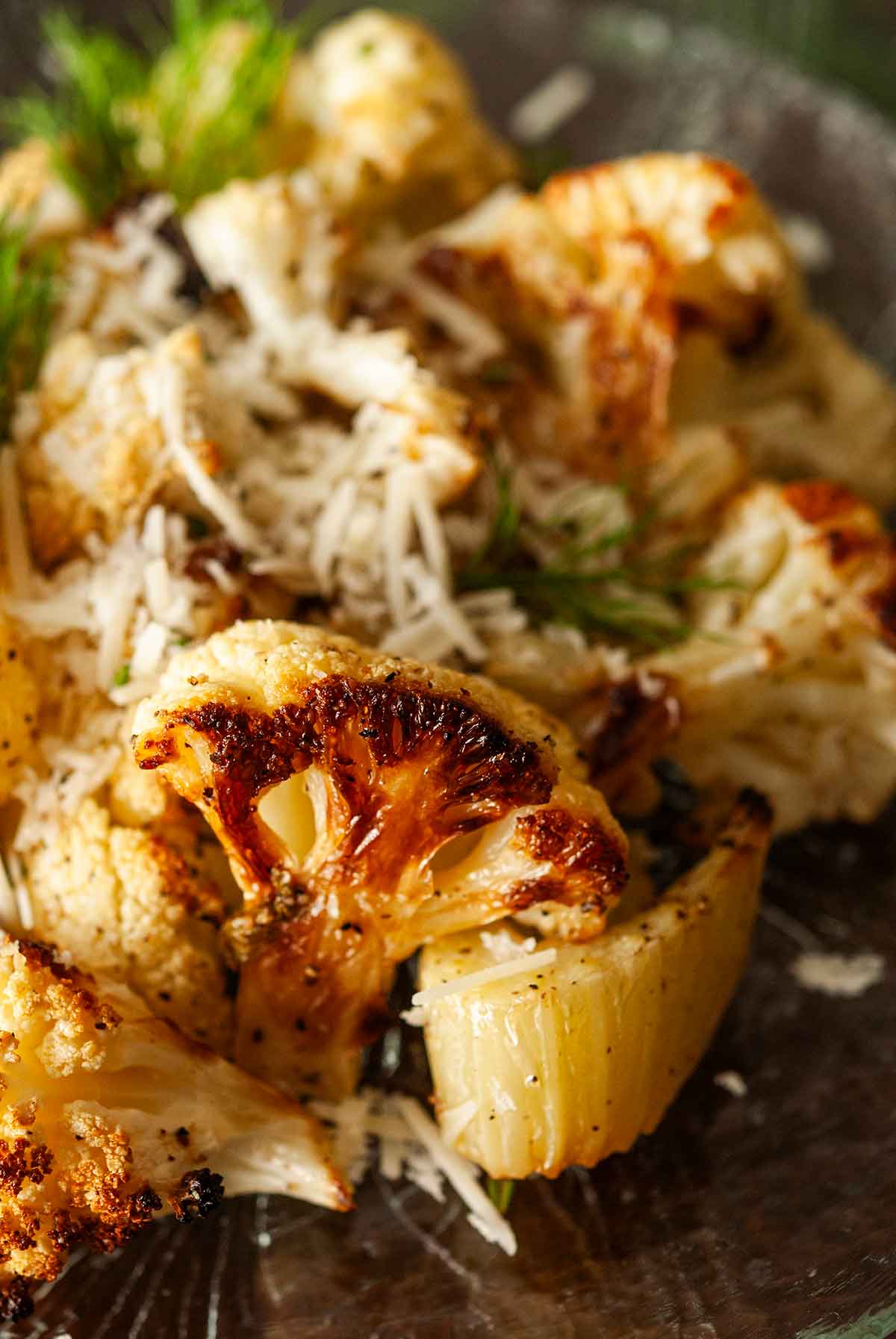 The sear on the side of a piece of cauliflower on a plate with fennel.