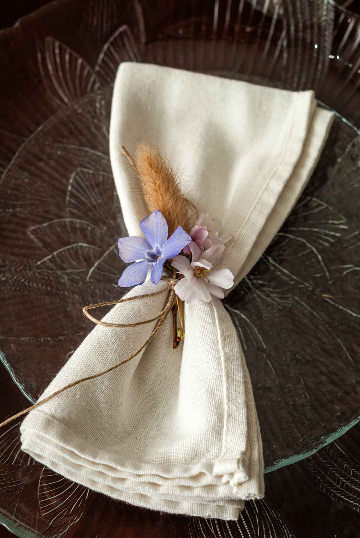 A napkin with flowers tied to the center on a plate.