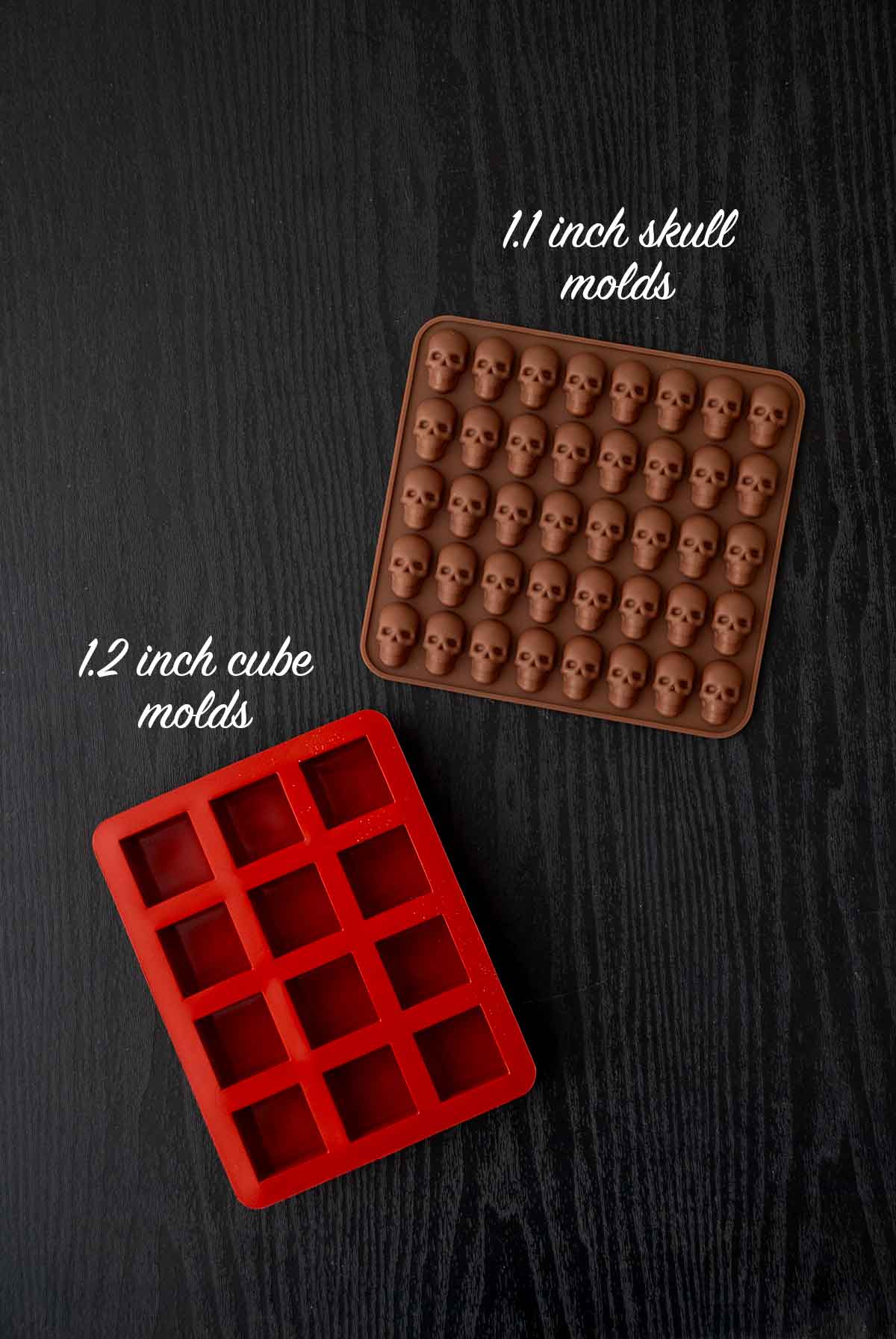 2 jello molds for making cubes and skulls on a table.